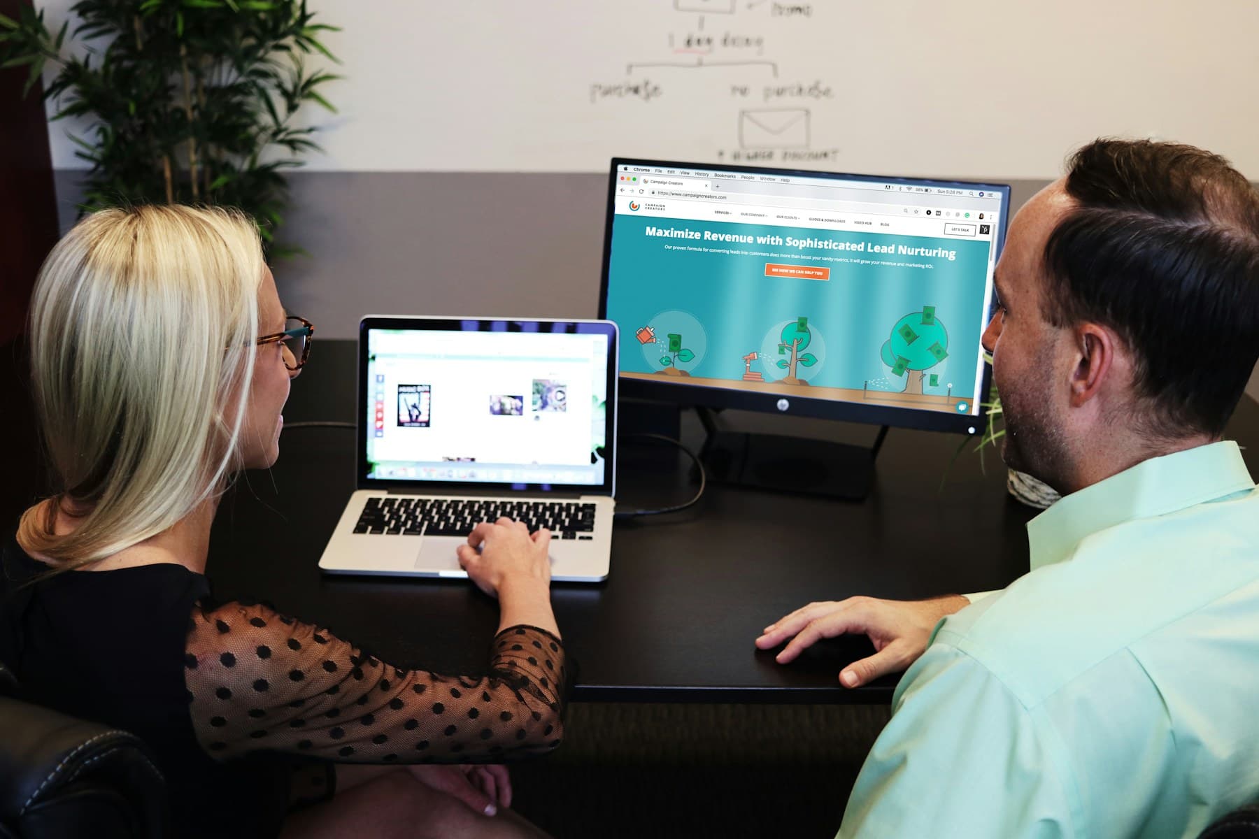 Two colleagues reviewing survey results on a laptop and monitor