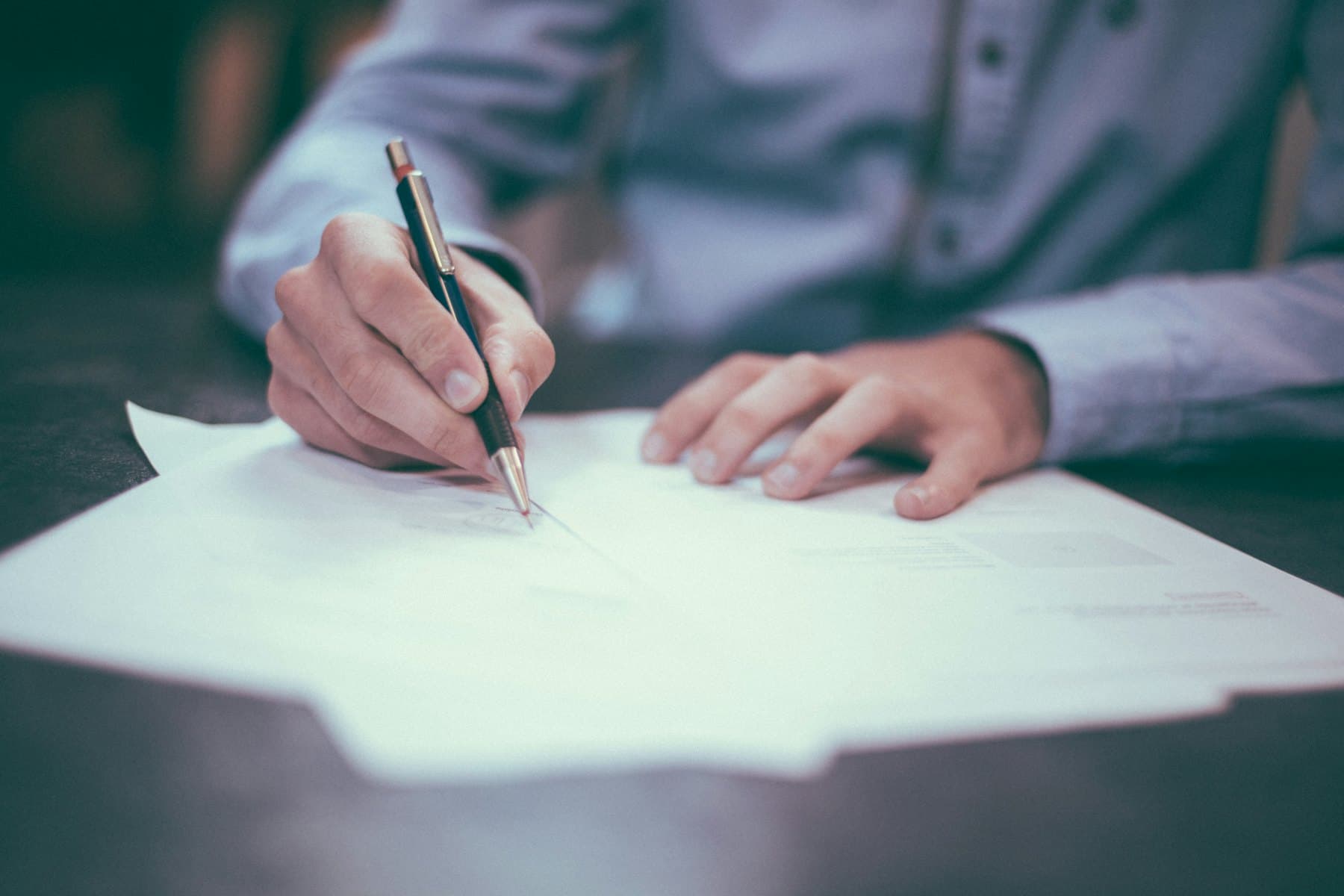 Person filling in a printed questionnaire with a pen at a desk