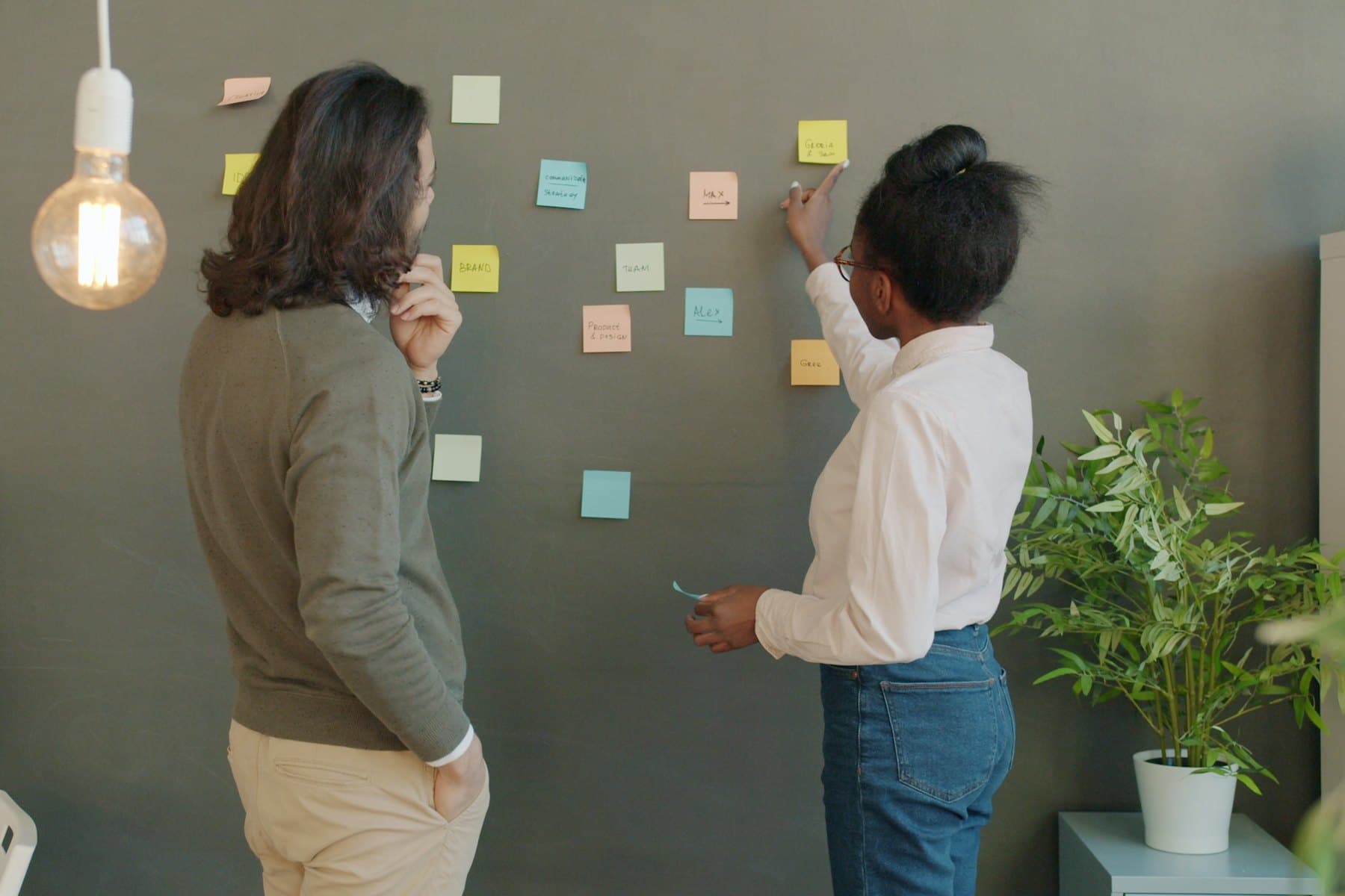 Two colleagues grouping handwritten sticky notes into themes on a wall